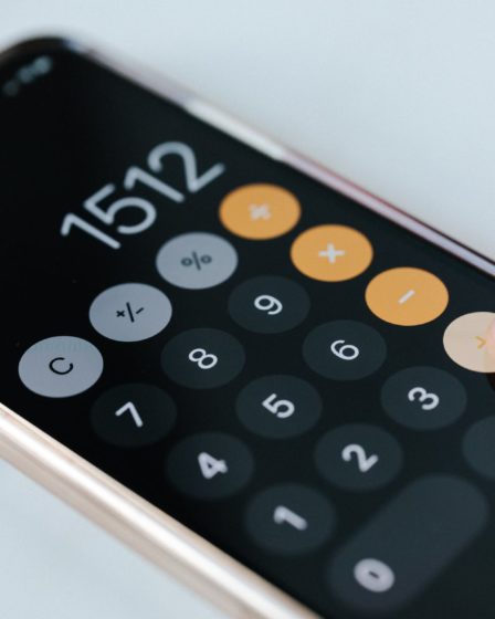 crop anonymous accountant using calculator app on smartphone